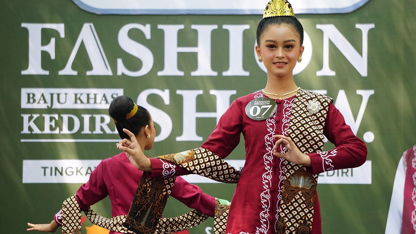 Model memakai setelan batik di panggung fashion show